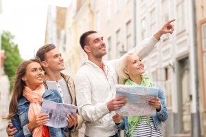 travel, vacation and friendship concept - group of smiling friends with city guide and map exploring city